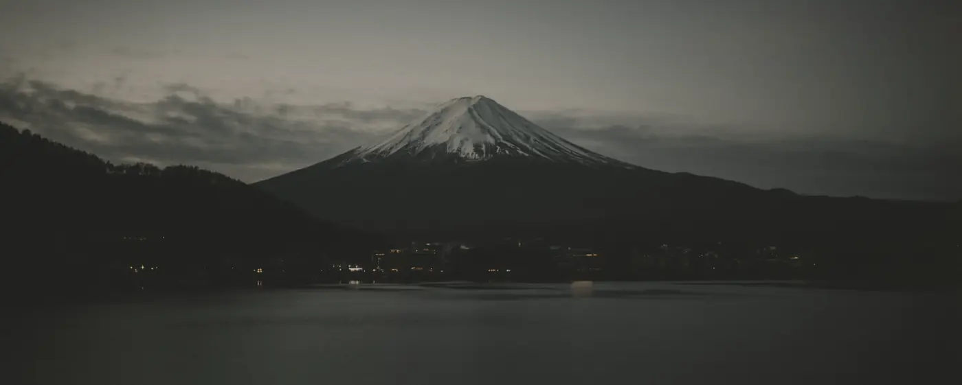 A volcanic peak above a dark lake at dusk