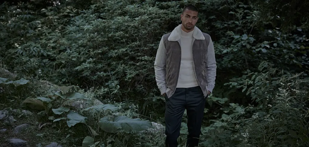 Emiliano Zapata campaign: a model in a shearling-collar jacket standing in dense greenery